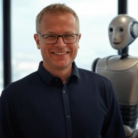 Robert Snyder of OPEN VCS smiling with a humanoid robot&nbsp;servant